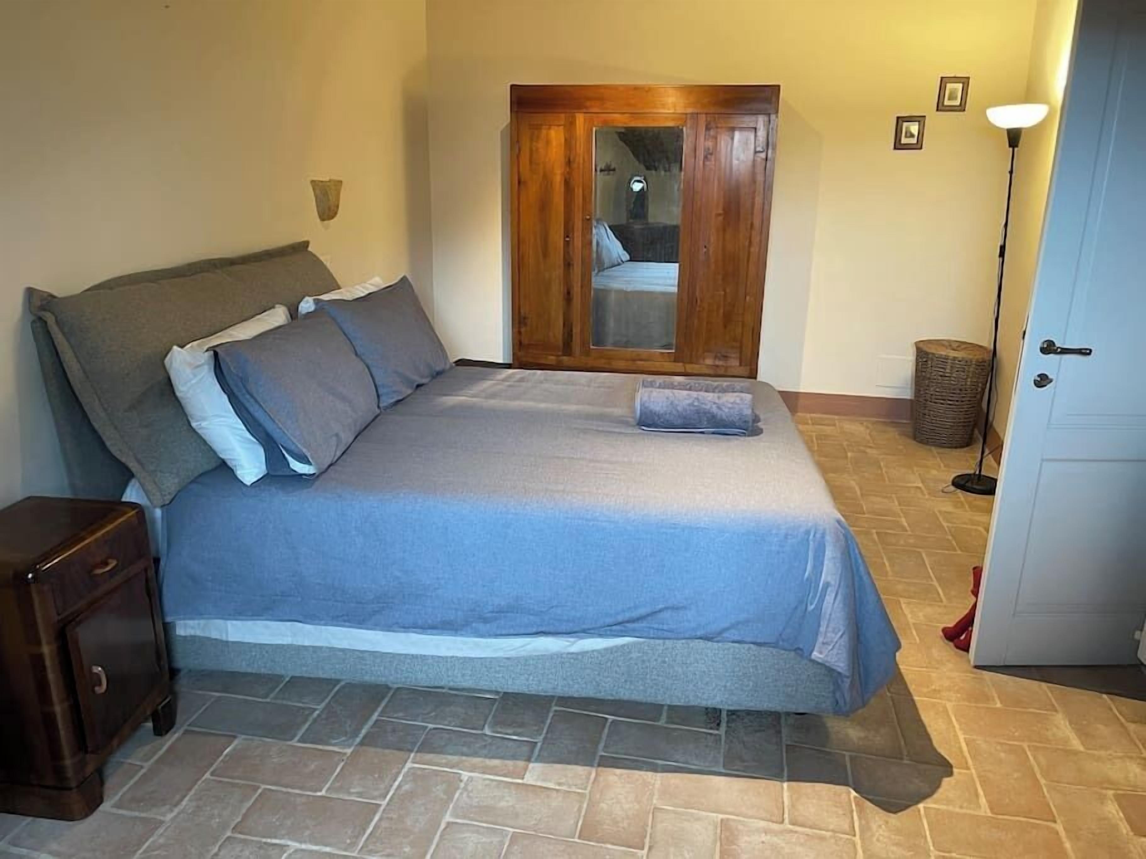Un dormitorio con cama, armario de madera y lámpara.