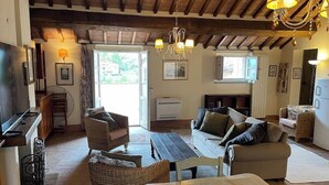 A cozy living room with a fireplace, wicker furniture, and a dining area. - 2 King Bed, 2 Full Bathroom Apartment in Città della Pieve, Umbria - Tuscany (Città della Pieve)