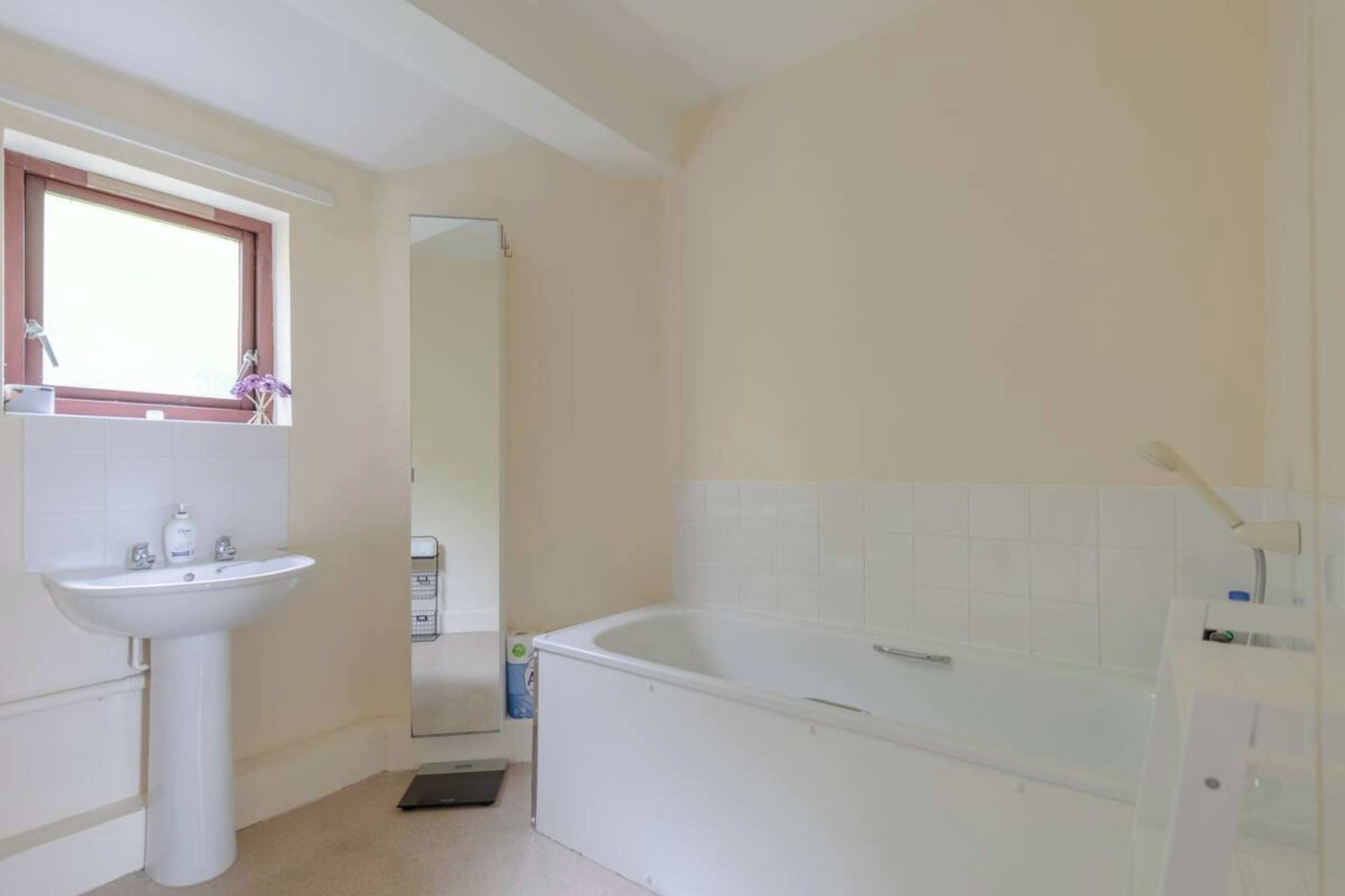 A bathroom with a sink, mirror, and bathtub.