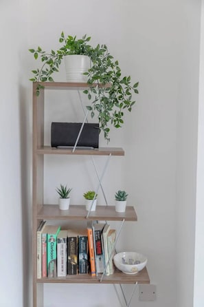 Cozy reading nook with a bookshelf featuring a potted plant, decorative accents, and a collection of books.