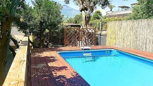 A wooden deck leading to a rectangular swimming pool with a metal ladder. - Villa with pool (Pompei)