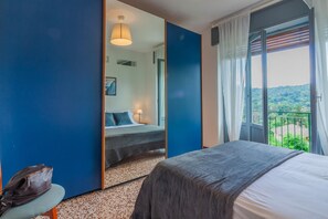 Une chambre à coucher avec un lit, une chaise, un miroir et une vue sur la verdure par la fenêtre.