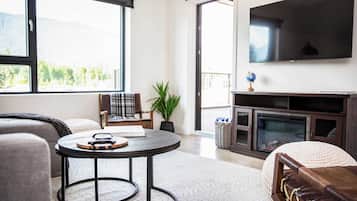 Una sala de estar con chimenea, televisor y un ventanal con vista a la montaña.