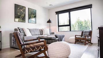 Una sala de estar moderna con un sofá, dos sillones mecedores, una mesa de centro y un ventanal grande.