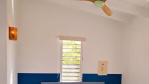 A bedroom with a bed, two bedside lamps, a ceiling fan, a window, and a wall-mounted light fixture. - 12B Flamingo by Bonaire Paradise (Kralendijk)