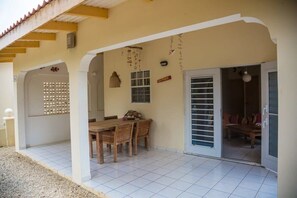 Un patio cubierto con una mesa y sillas, una puerta corrediza de vidrio y piso de baldosas.