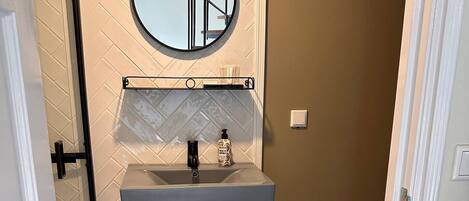 A bathroom with a sink, mirror, and towel rack.