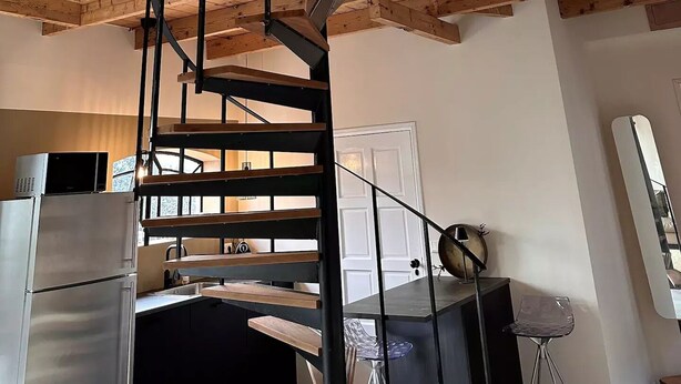 Eine moderne Küche mit integriertem Kühlschrank, einem Essbereich mit Tisch und Stühlen sowie einer Holzbalkendecke.