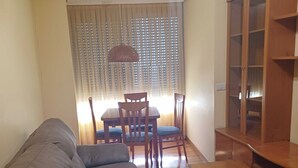 A living room with a sofa, dining table, chairs, and a wooden cabinet. - Apartamento Vigo Playa-ciudad II (Vigo)
