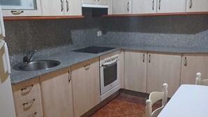 A kitchen with cabinets, a sink, a stove, and a table. - Apartamento Vigo Playa-ciudad II (Vigo)