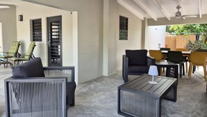 Ein moderner Außenbereich mit Metallmöbeln, einem Deckenventilator und Blick auf einen Garten.