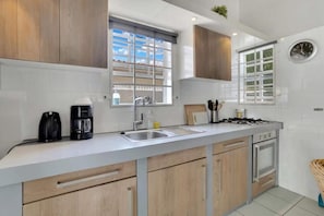 A modern kitchen with wooden cabinets, a built-in oven, a sink, and a window with a view.