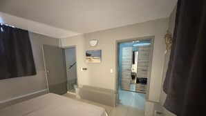 Ein Schlafzimmer mit Bett, ein Badezimmer mit Spiegel und ein Flur, der zu einem Kleiderschrank führt.