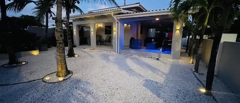 A modern house with a gravel driveway and palm trees.