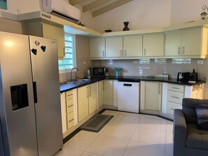 A modern kitchen with white cabinets, a stainless steel refrigerator, a microwave, and a dishwasher.