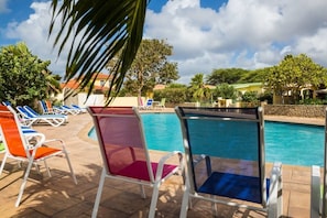 Un área de piscina con sillones de descanso y vista despejada a la piscina.