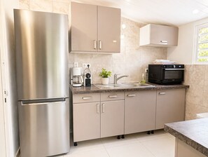 A modern kitchen with a stainless steel refrigerator, a coffee maker, a microwave, and a sink.