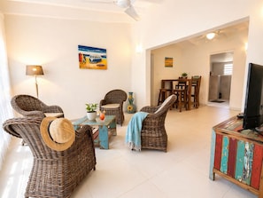 A living room with wicker furniture, a television, and artwork on the walls.