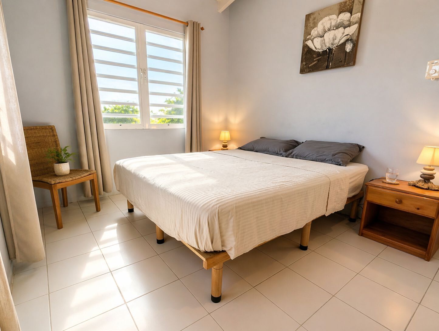 Une chambre à coucher avec un lit, une chaise, une table de chevet, une lampe et une fenêtre avec des rideaux.