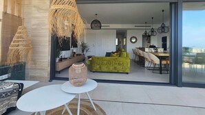 A modern living area with a sofa, dining table, and hanging wicker light fixtures. - Casa la Vista • 2 Bedroom • Sunny terrace • Camporrosso Stone Valley Resort (Finestrat)