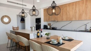 A modern kitchen with wooden cabinets, a marble countertop, and pendant lights. - Casa la Vista • 2 Bedroom • Sunny terrace • Camporrosso Stone Valley Resort (Finestrat)