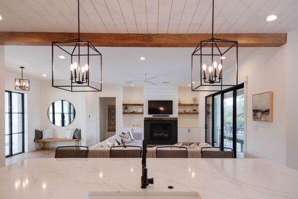 A spacious living area with a large marble floor, a fireplace, a TV, and a sofa set.