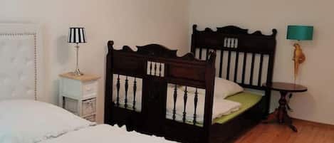 A bedroom with two beds, a nightstand, a lamp, and a small table.