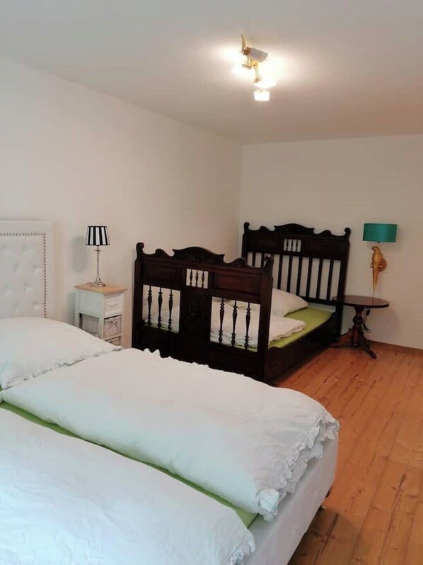 A bedroom with two beds, a nightstand, a lamp, and a small table. - Vacation apartment Bergblick (Königstein)