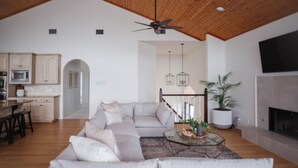 A modern living room with a sectional sofa, a glass coffee table, and a fireplace.