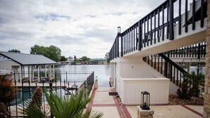 A waterfront property with a pool, a dock, and a staircase leading to a covered area.
