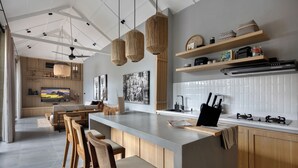 Una cocina moderna con una isla central, taburetes de madera y elegantes lámparas colgantes de mimbre.