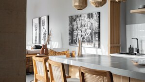 Una cocina moderna con una isla central, sillas de madera y lámparas colgantes de fibra.