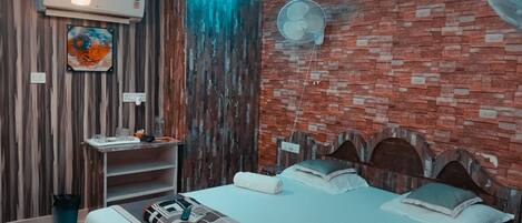 A modern bedroom with a brick wall, a ceiling fan, a mounted air conditioner, and a bed with a patterned bedspread.