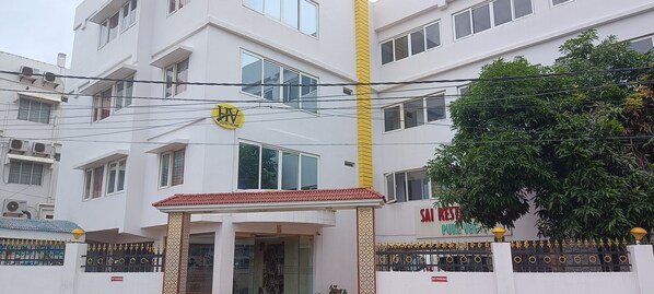 Ein mehrstöckiges Hotel mit einem auffälligen, gelben vertikalen Streifen, einer Beschilderung mit dem Schriftzug "HOTEL RELEVANT" und einem Schild, auf dem "SAI RESTAURANT PURE VEG" steht.