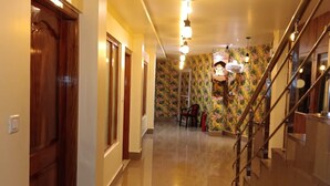 A hallway with wooden doors, a staircase with metal railings, and a patterned wall. - Hotel Vedant (Port Blair)