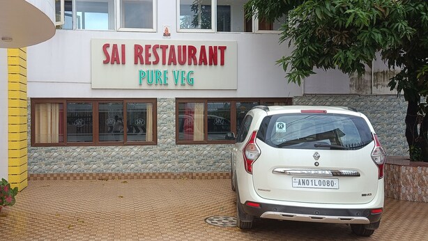 A white car parked in front of Sai Restaurant Pure Veg. - Hotel Vedant (Port Blair)