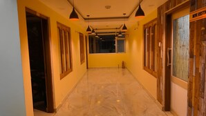 A hallway with marble flooring, pendant lighting, and wooden doors. - Hotel Vedant (Port Blair)