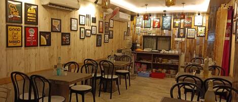 Un restaurante con paredes de madera, cuadros enmarcados y una zona de bar. Mesas y sillas dispuestas para comer.