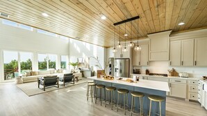 A spacious kitchen with a large island, bar stools, and a view of the outdoors.