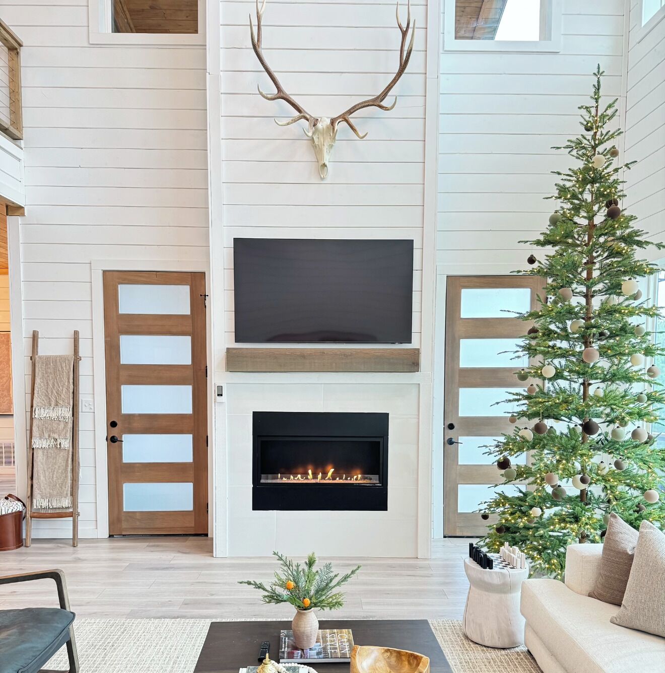 Ein Wohnzimmer mit Kamin, einem Wand-Fernseher und einem Weihnachtsbaum.