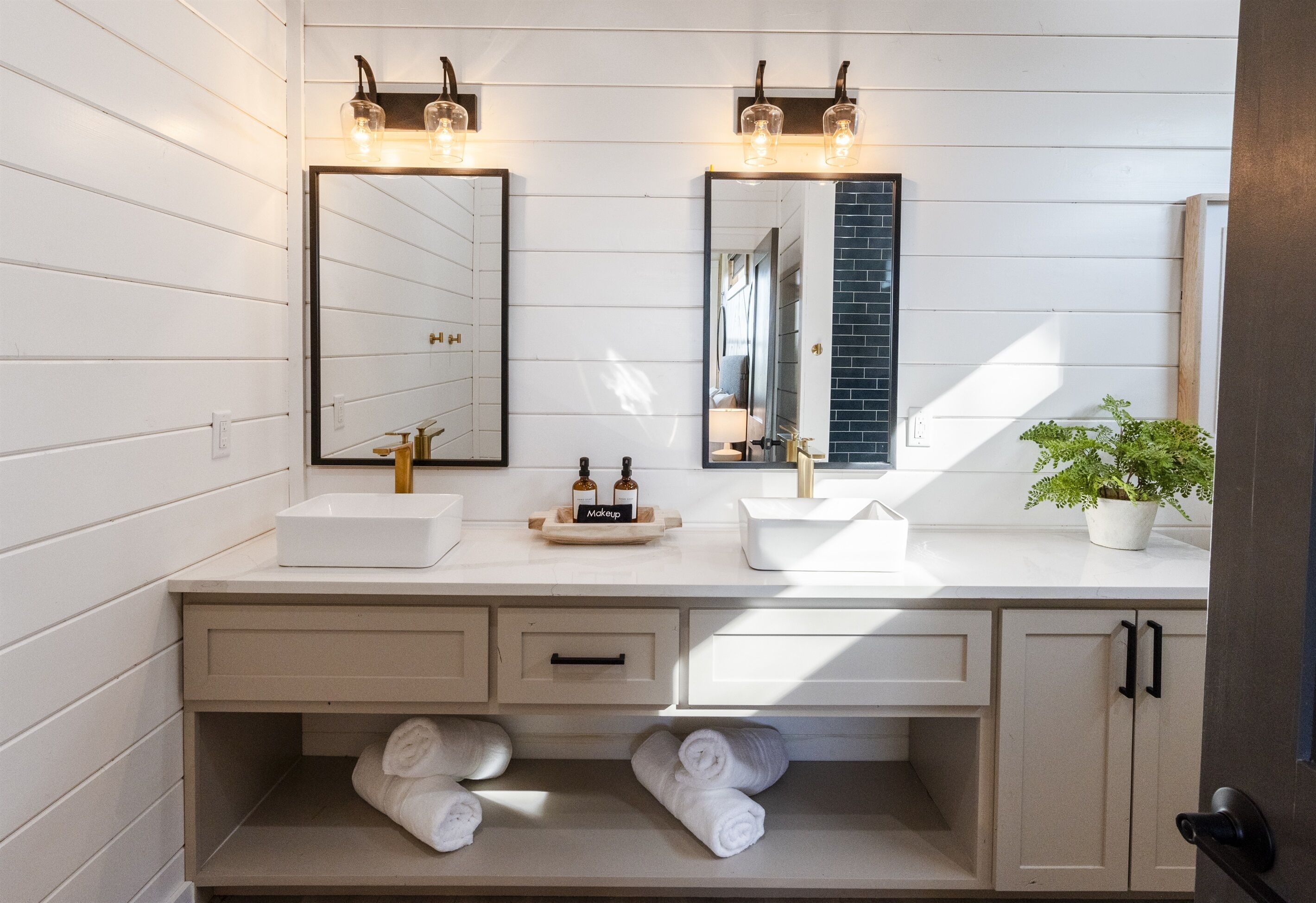 A bathroom with two sinks, a mirror, and a towel rack.