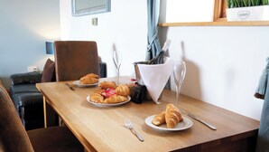 Una mesa de comedor con cruasanes, una botella de champán y una copa.
