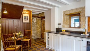 Eine gemütliche Küche mit Steinwand, Holztür und Essbereich mit Tisch und Stühlen.