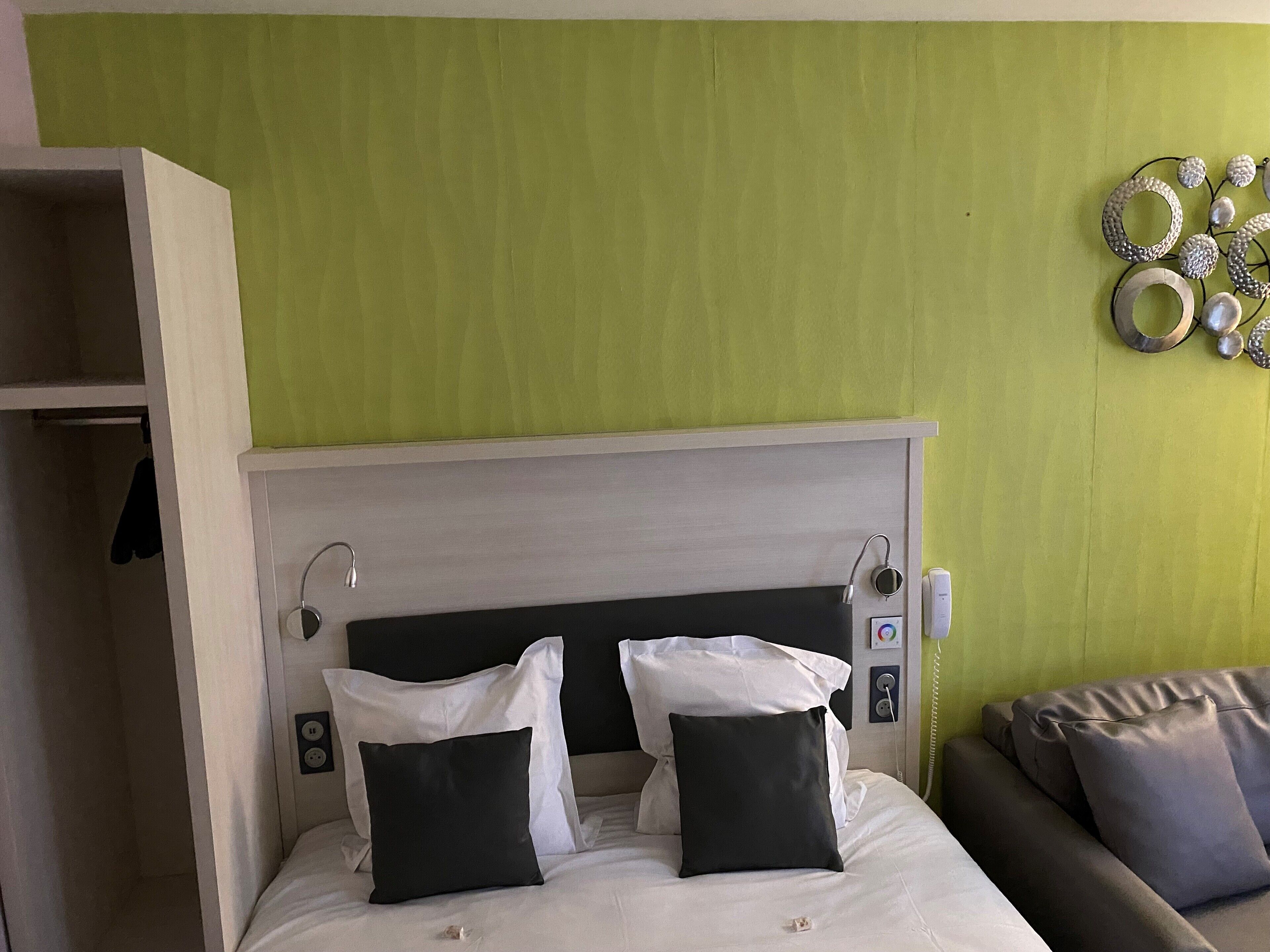 Ein Hotelzimmer mit Bett, Nachttisch, Wandpaneel und einer dekorativen Wandgestaltung.