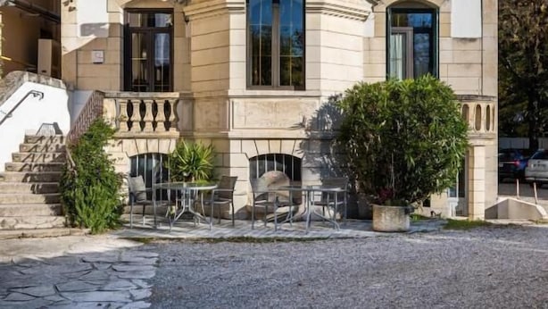 A two-story hotel with a classic architectural style, featuring a central entrance with a balcony and outdoor seating area. - Hôtel Beausoleil (Montélimar)