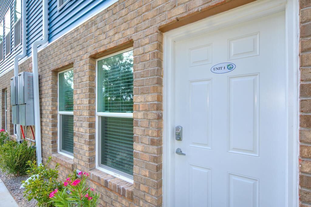 A brick building with a white door labeled "UNIT 1".