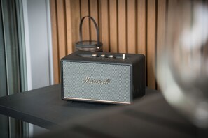 Ein Marshall Lautsprecher auf einem schwarzen Tisch vor einer Holzwand.