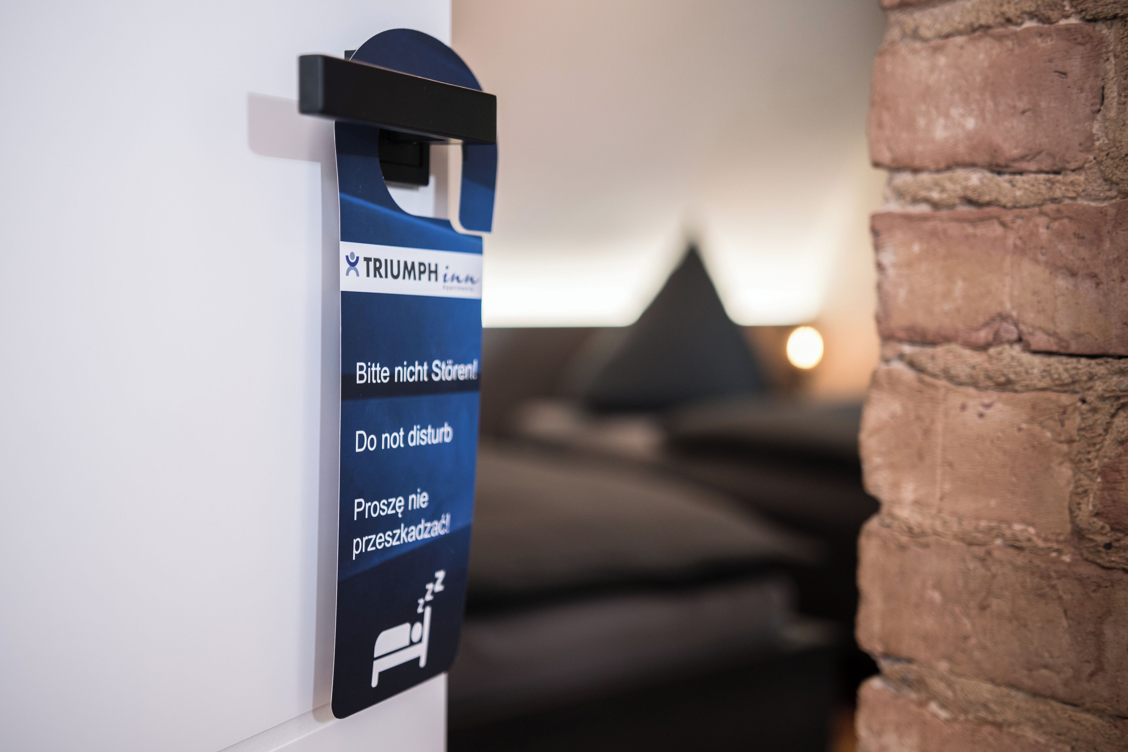 Un cartel con instrucciones en varios idiomas para una habitación, que incluye un símbolo de cama y un objeto triangular al fondo.