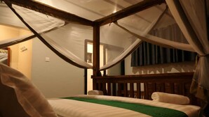 Ein Schlafzimmer mit einem Himmelbett, einer grünen Tagesdecke und einem Baldachin.