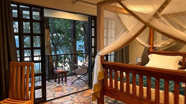 Ein Schlafzimmer mit einem hölzernen Bett, einem Baldachin und einem Steinboden.